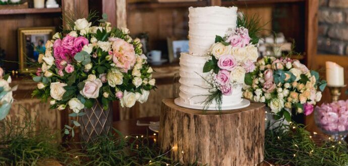 画像：切り株の上に載せられたウエディングケーキとグリーンや花の装飾