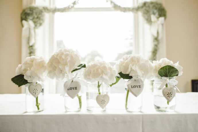 画像：メインテーブルに置かれた5つの花瓶とそこに挿した1輪の白い花弁の多い丸い花