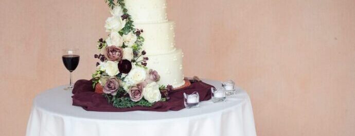 画像：ウエディングケーキからバラが流れ落ちるようにデザインされ、ワインレッドのクチュールをケーキの下に敷いたケーキ台