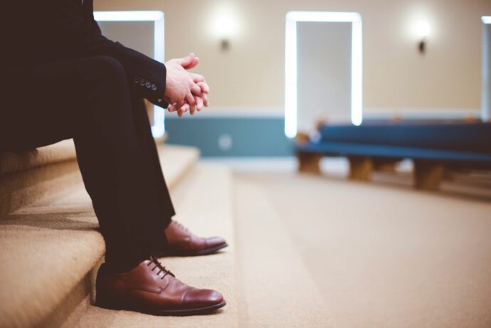 画像：教会の段差に腰掛けるスーツ姿の男性