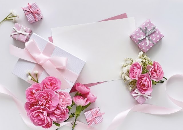 画像：ピンクの花と白い封筒、ピンクのリボンがかかったプレゼントボックス