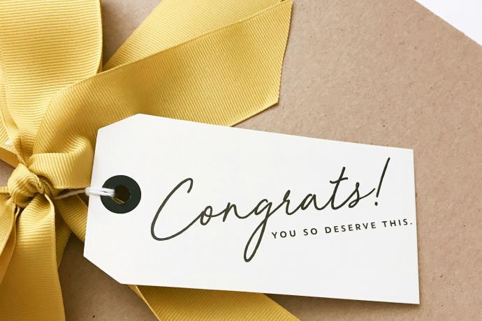 画像：congratulats! と書かれたタグの付いたプレゼントボックスの黄色いリボン部分のアップ
