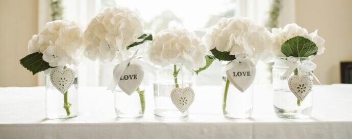 画像：5つの花瓶に分けて活けられた白い大振りの花がメインテーブルに並んでいる