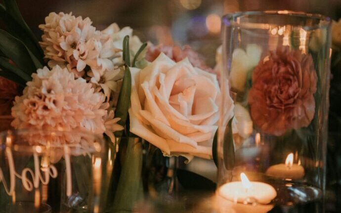 画像：ガラス瓶の中に入れられたバラやアロマキャンドル、一輪挿しなどが飾られているテーブル