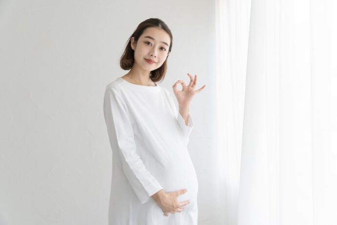 画像：OKサインを作る白い服の妊婦