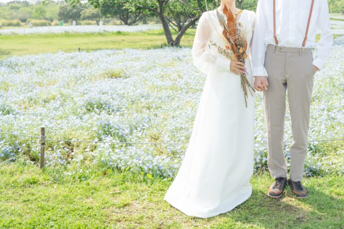 画像：花畑で寄り添い立つ花嫁と花婿